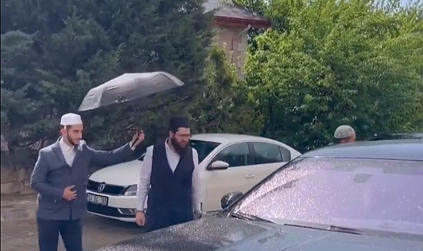 Mürteci Menzil Örgütünün Elebaşının Oğlu Kendini Bir Şey Zannetti: Lüks Aracından İnerken Müridine Şemsiye Tutturdu